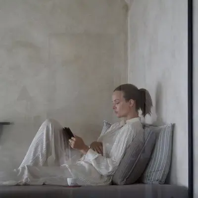 Josephine Skriver reading book in all-white lounge set