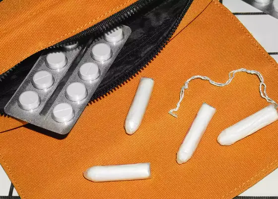 Orange pouch with a birth control packet and tampon falling out 