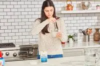 Woman mixing glass of water with Procaps Marine Collagen Peptides powder