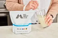 Person mixing Momentous Collagen Peptides in water
