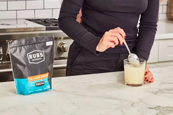Person stirring Bubs Naturals Collagen Peptides into a glass of water