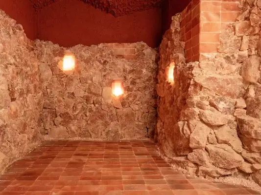 A red clay-colored salt room with glowing candlelight.
