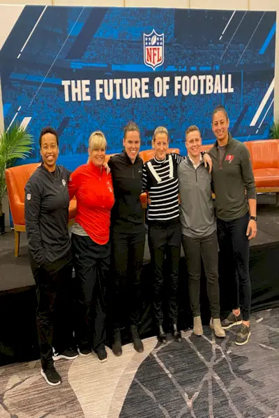 en person som har på seg en blå sportsjakke og caps under et utendørsarrangement