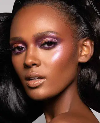 model wears shimmering purple eyeshadow with highlighted complexion