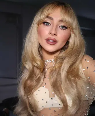 Sabrina Carpenter wears a glamorous makeup look with rhinestone details on the eyes