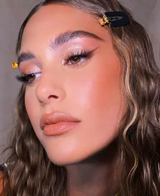 model wears glistening eye makeup on lids with winged liner