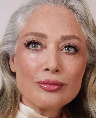 model wears natural makeup look with long lashes and glossy pink lips