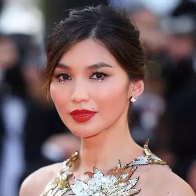 Gemma Chan with bold red lips and crystals beneath her eyes