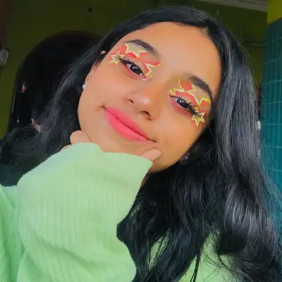 Makeup artist wears red and yellow star eye makeup and pink lipstick