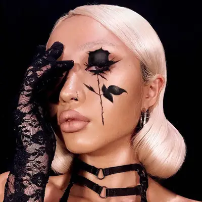 Makeup artist wears black rose face paint design on eye and cheek