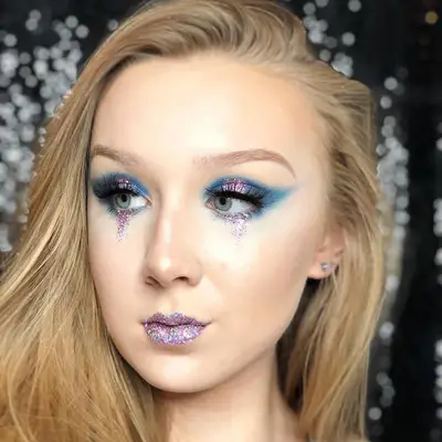 Makeup artist wears a blue and purple look with glitter tears and lips