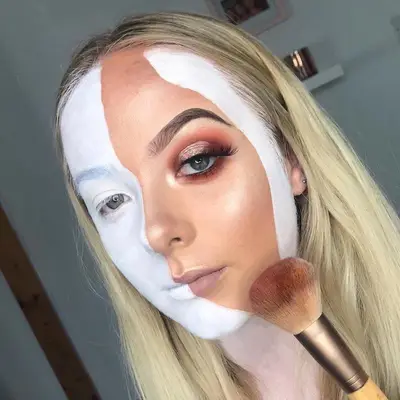 Makeup artist wears white face paint with sliver of full glam makeup