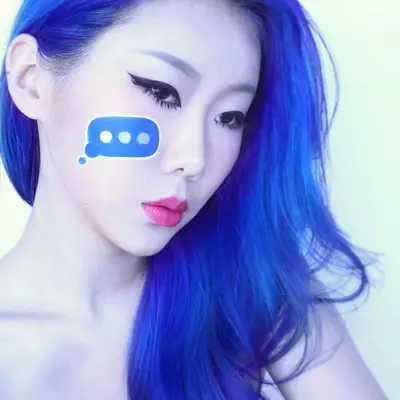 Makeup artist with blue hair wears winged liner and typing bubble face paint on cheek