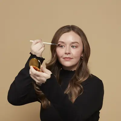Woman applies a neutral eyeshadow to her eyelids