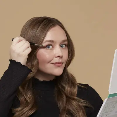 Woman applies eyeshadow to her eyelid