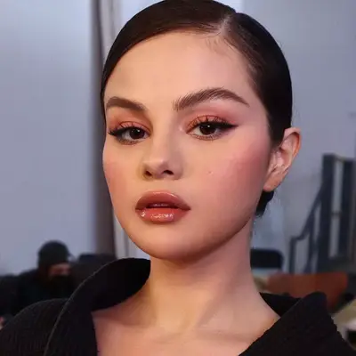 Selena Gomez with winged eyeliner, pink eyeshadow, and glossy pink lips