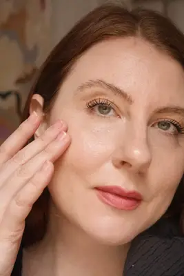 model is applying foundation to the face with their fingers