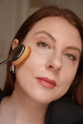 model is applying foundation to the face with a foundation brush