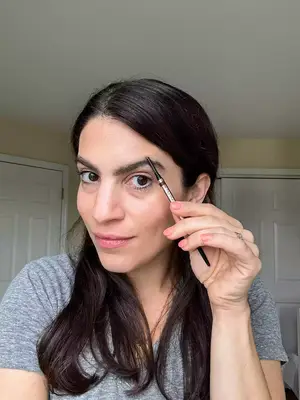 A person using the spoolie of the PATRICK TA Major Brow Defining Pencil on their brow