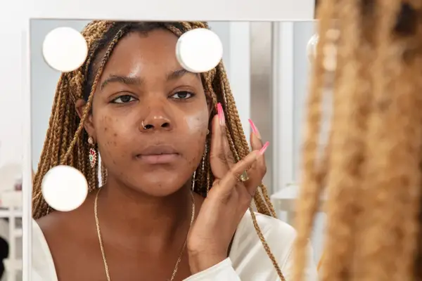 Person dabbing Tatcha The Silk Canvas Face Protective Primer onto their face in a mirror