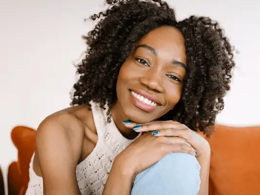A woman with her head tilted on top of her hands as she holds her knee into her body