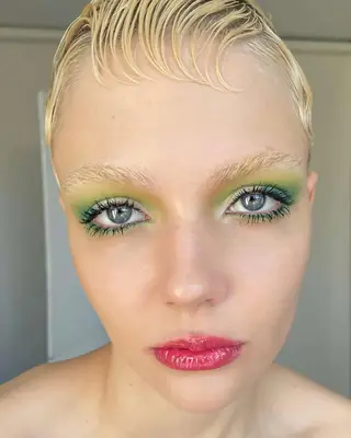 Person with bleached eyebrows and green eye makeup 