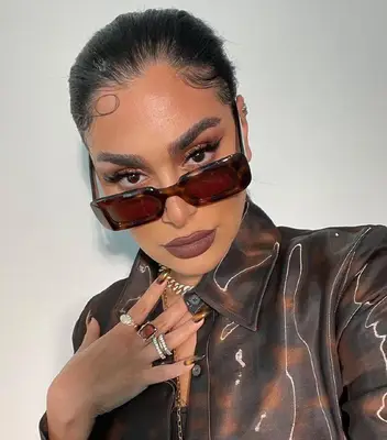 Woman wearing brown lipstick, eyeshadow, and tortoise sunglasses and jacket