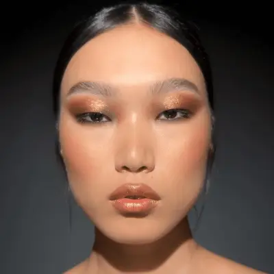 model wearing sparkly bronze eyeshadow and lipstick
