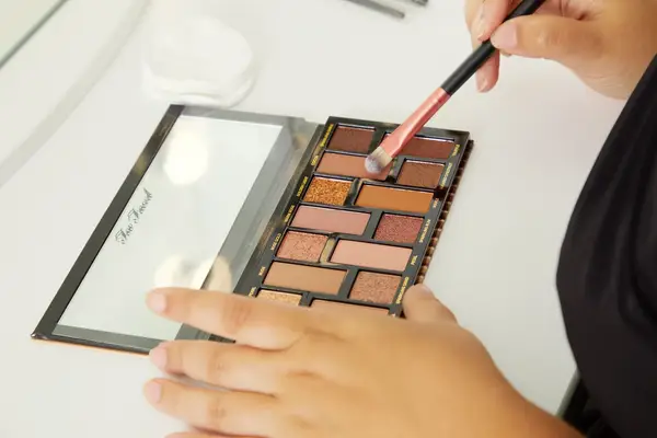 Hand dipping brush into the Too Faced Born This Way The Natural Nudes Eye Shadow Palette