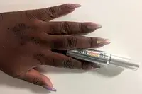 A person holds a tube of Benefit Cosmetics They