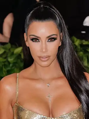 Kim Kardashian wearing gold dress, half-up half-down hairstyle, and 
