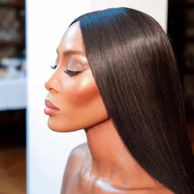 Naomi Campbell wears shimmery eyeshadow, highlighter, bronzer, foundation, and neutral pink lipstick