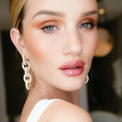 Rosie Huntington-Whiteley with warm-toned eyeshadow, blue eyes, and pink shimmery lipstick
