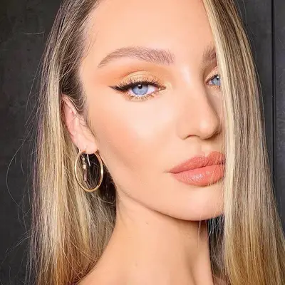 Candice Swanepoel with light warm-toned eyeshadow, winged eyeliner, blue eyes, and peachy lipstick