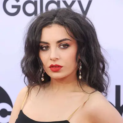 Charli xcx in 2015 rocking messy waves and a red lip with a smokey black eye.