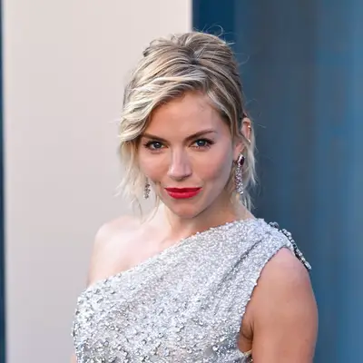 Sienna Miller with diagonal eyebrows and sequin dress attends the 2022 Vanity Fair Oscar Party