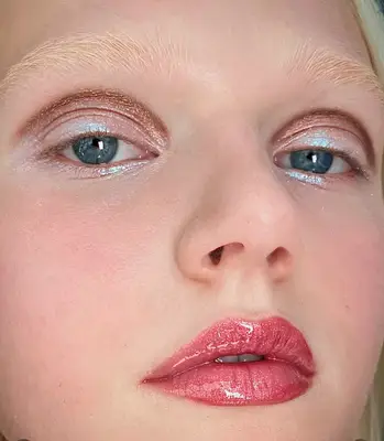 model wears holographic eyeshadow with glossy lips