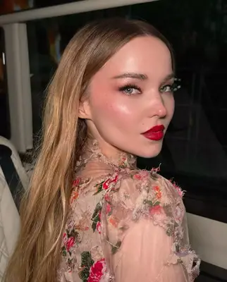 Rachel Zegler with curly black hair and a Fuschia-toned makeup look