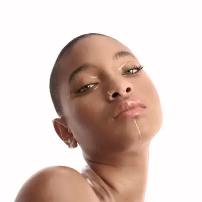 Willow Smith with graphic gold makeup look featuring eyeliner and chin lines and neutral lip gloss