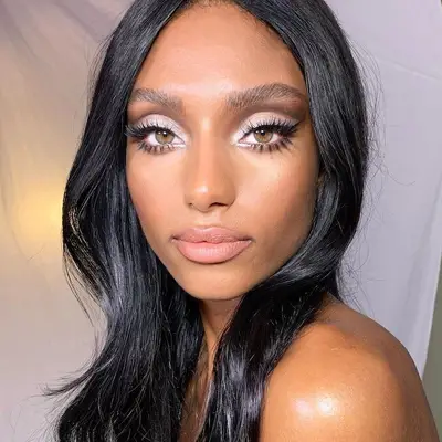 Woman with silvery white eyeshadow, mod lashes, green eyes, and subtle pink blush and lipstick