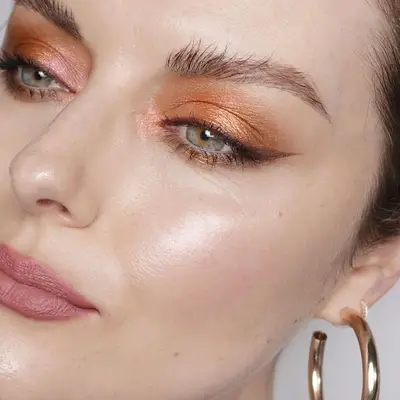Katie Jane Hughes with neutral orange eyeshadow, green eyes, and pink blush and lipstick