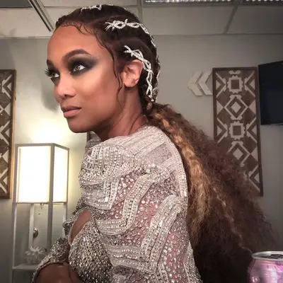 Tyra Banks with smoky eyeshadow, green eyes, a cornrowed low ponytail hairstyle, and neutral makeup