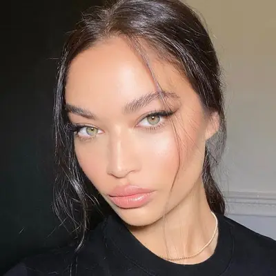 Shanina Shaik with minimal dewy makeup, subtle black eyeliner, and green eyes