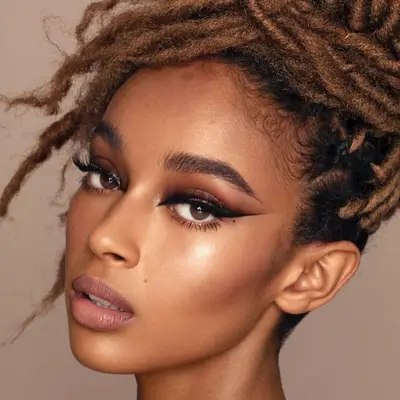 Woman with locs updo and brown and black eye makeup look with sharp eyeliner