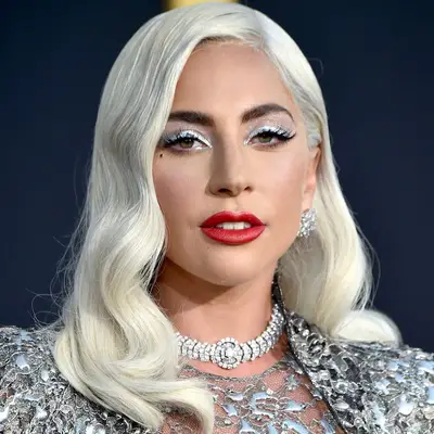 Lady Gaga with shimmery silver eyeshadow, green eyes, red lipstick, and platinum old Hollywood waves