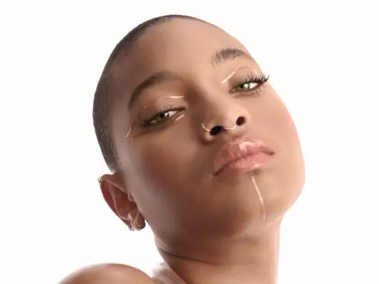 Willow Smith wears gold graphic makeup on her green eyes and chin