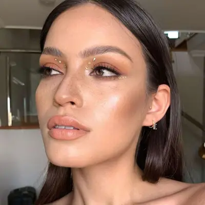 Bronze makeup with three gemstones along the wing line and three in the inner corner of the eye.