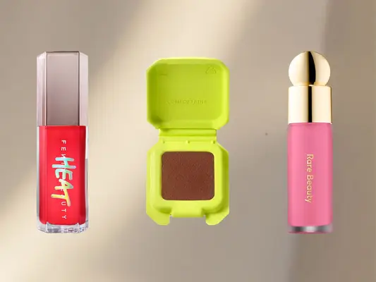 Fenty Glossbomb Heat, Half Magic Blus. and Rare Beauty Blush against a beige, sunlit background