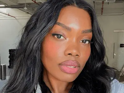 Model with long black hair and bright pink blush 