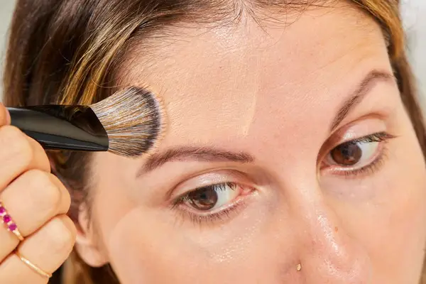 A person applies foundation to their forehead using a Sephora Collection PRO Foundation Brush #47